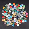 A collection of heart-shaped amethyst crystal stones in various shades of green, pink, blue, and yellow scattered on a dark s