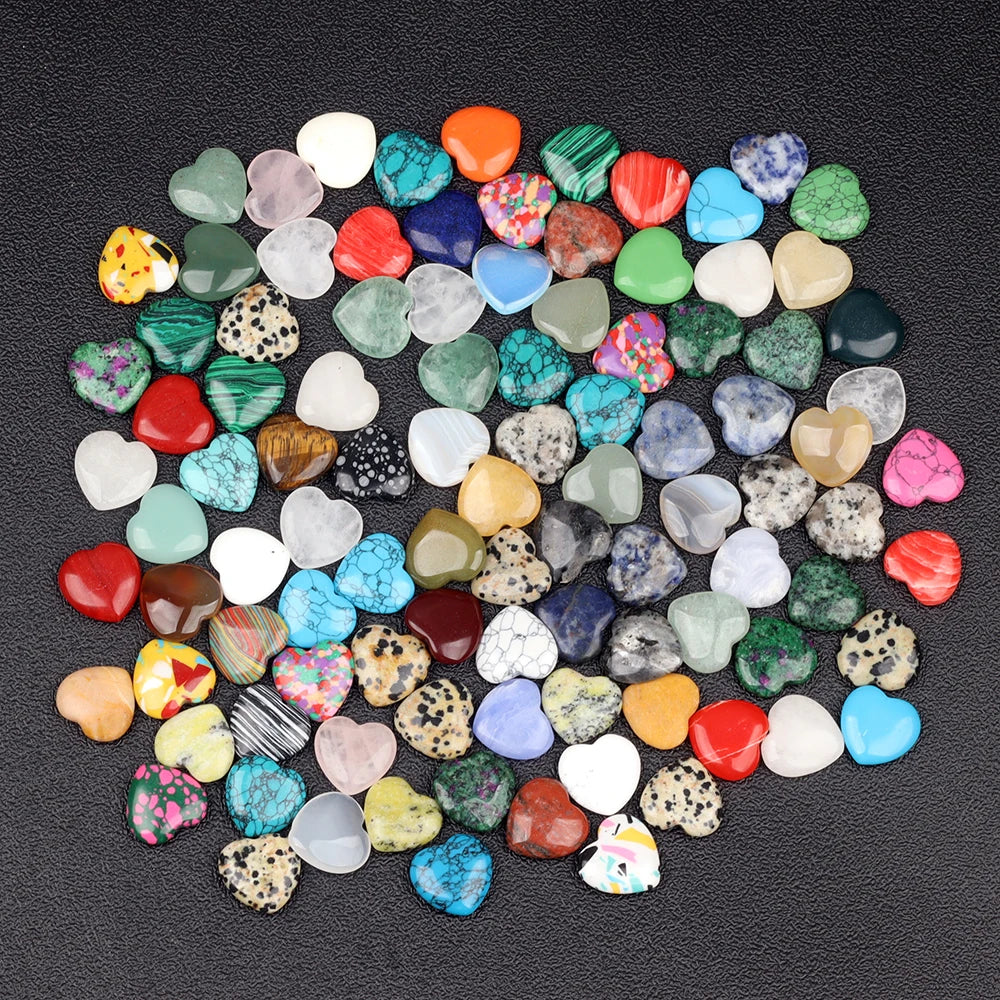 A collection of heart-shaped amethyst crystal stones in various shades of green, pink, blue, and yellow scattered on a dark s