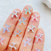 A hand displays various clear and iridescent balloon puppy nail art charms on the fingernails.