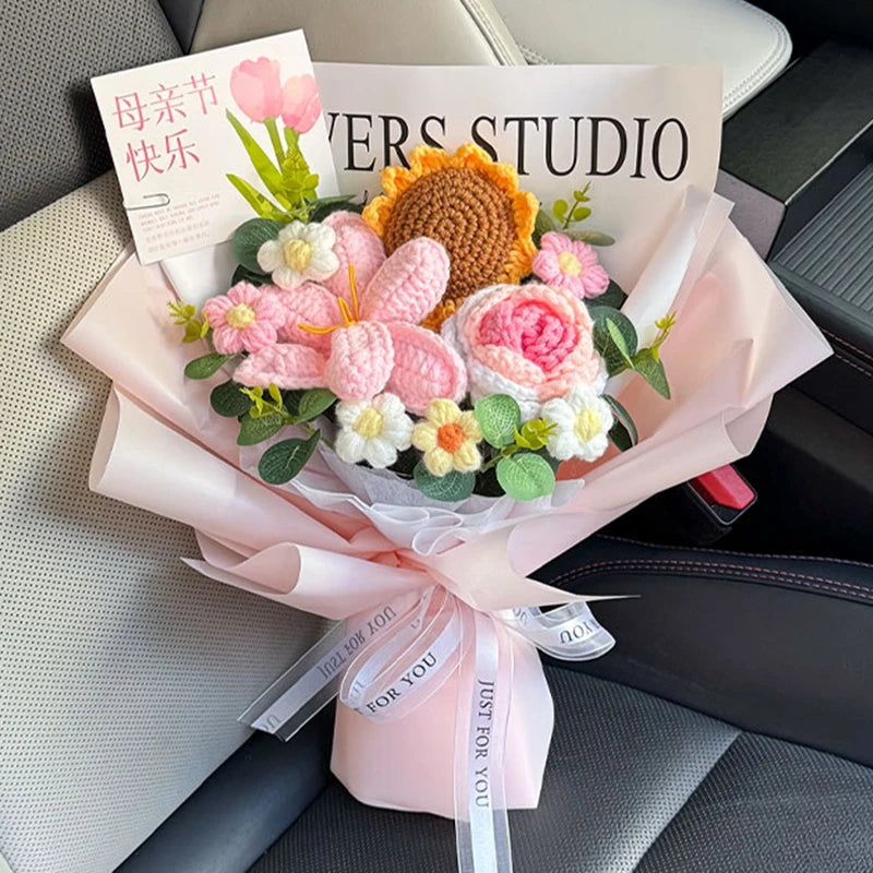 A bouquet of handmade crochet flowers in pink and yellow tones wrapped in light pink paper.