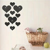 A set of black heart-shaped mirror wall stickers displayed against a white paneled wall.