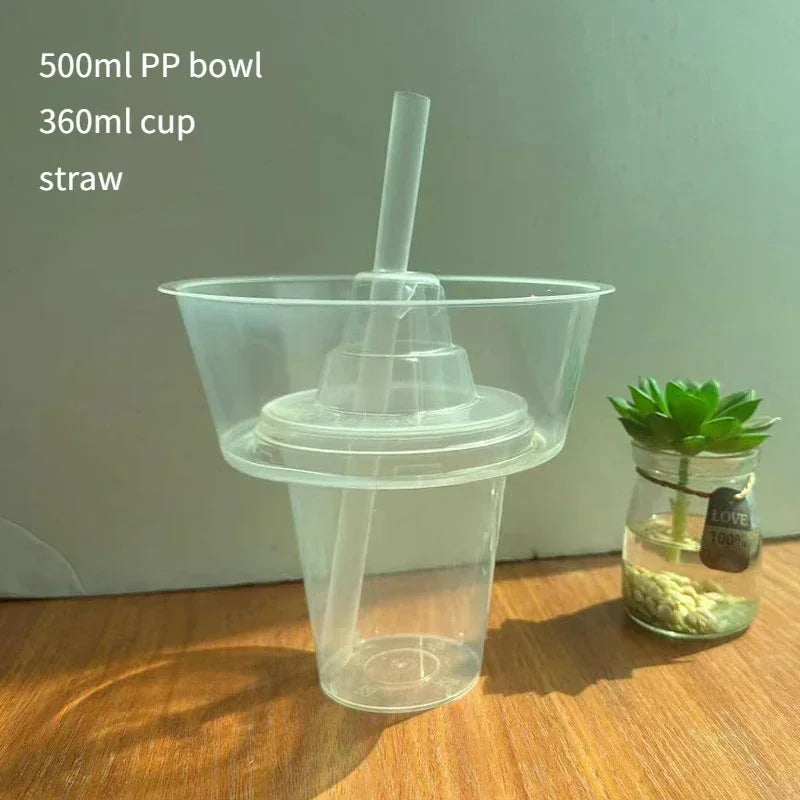 A clear plastic bowl with a straw is shown next to a small glass jar containing green leaves.