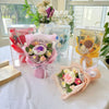 A display of handmade crochet flower bouquets in clear glass jars with pink and yellow accents.