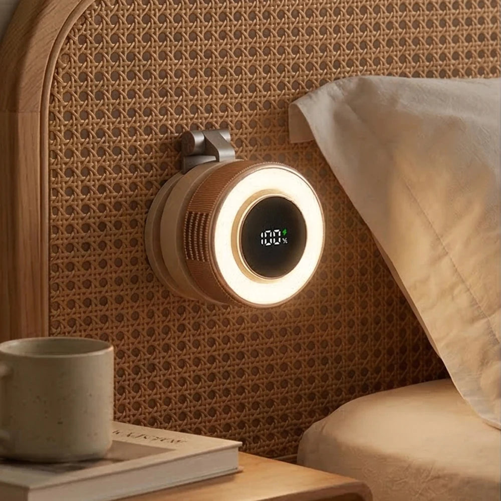 A magnetic bladeless handheld fan with a round light illuminates a textured wall next to a cup and book.