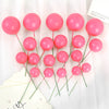A set of twenty pink spherical ball cake toppers on thin green sticks displayed against a white background.