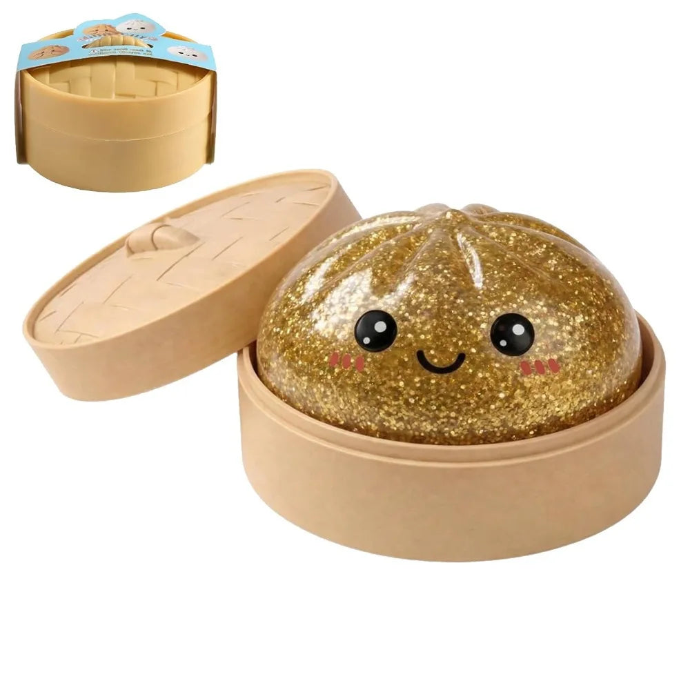 A golden glitter squishy toy shaped like a smiling dumpling is shown in its cardboard container.
