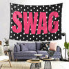 A pink polka dot tapestry featuring the word SWAG displayed on a black background.