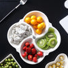 Weiße Keramik-Servierplatte gefüllt mit frischen Snacks wie Zitrusfrüchten, Kiwi und Erdbeeren.