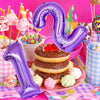 A purple foil number balloon shaped like the number 9 floats above a stack of pancakes and colorful treats.