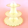 A three-tier rainbow cupcake stand with light yellow and orange accents for dessert displays.
