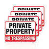 A set of red and white signs with the text PRIVATE PROPERTY NO TRESPASSING on them.