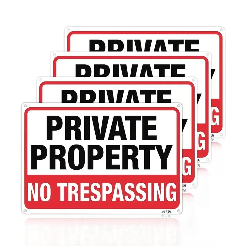 A set of red and white signs with the text PRIVATE PROPERTY NO TRESPASSING on them.