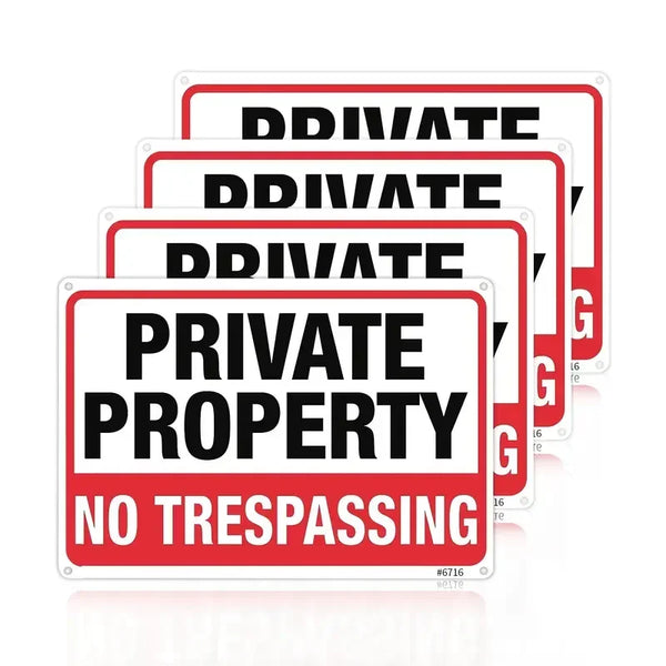 A set of red and white signs with the text PRIVATE PROPERTY NO TRESPASSING on them.