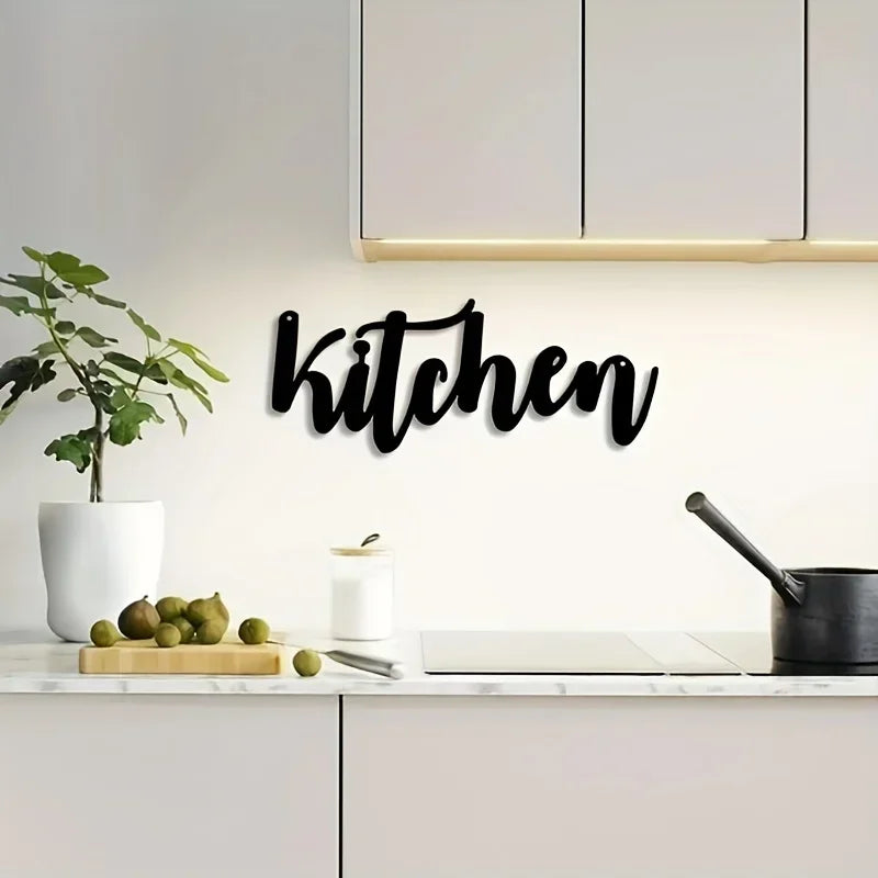 Black script wall art spelling 'kitchen' mounted on a white kitchen backsplash