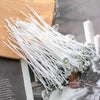 A bundle of white smokeless cotton candle wicks is displayed on a wooden surface.