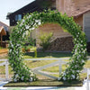An archway made of artificial ivy vine garland with white flowers set in a garden or yard.