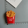 A bright orange container filled with golden french fries, used as a display for fridge magnets.