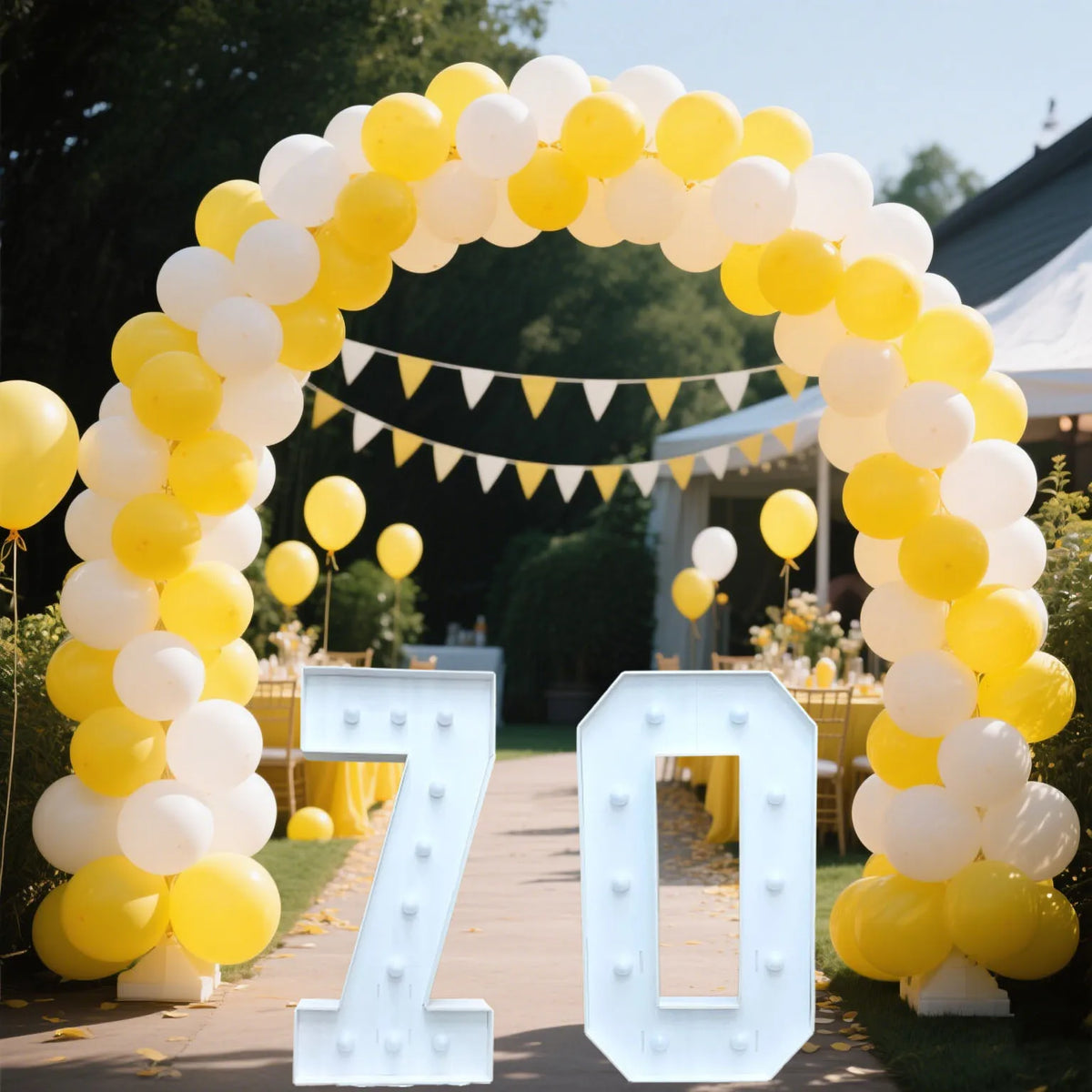 A large archway made of yellow and white balloons framing a light-up marquee number sign displaying 70.
