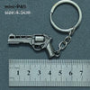 A silver miniature P45 pistol model attached to a metal keyring, measured against a ruler.