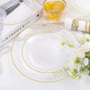 A set of white disposable dinner plates with hammered gold rims and a natural linen napkin displayed on a white surface.