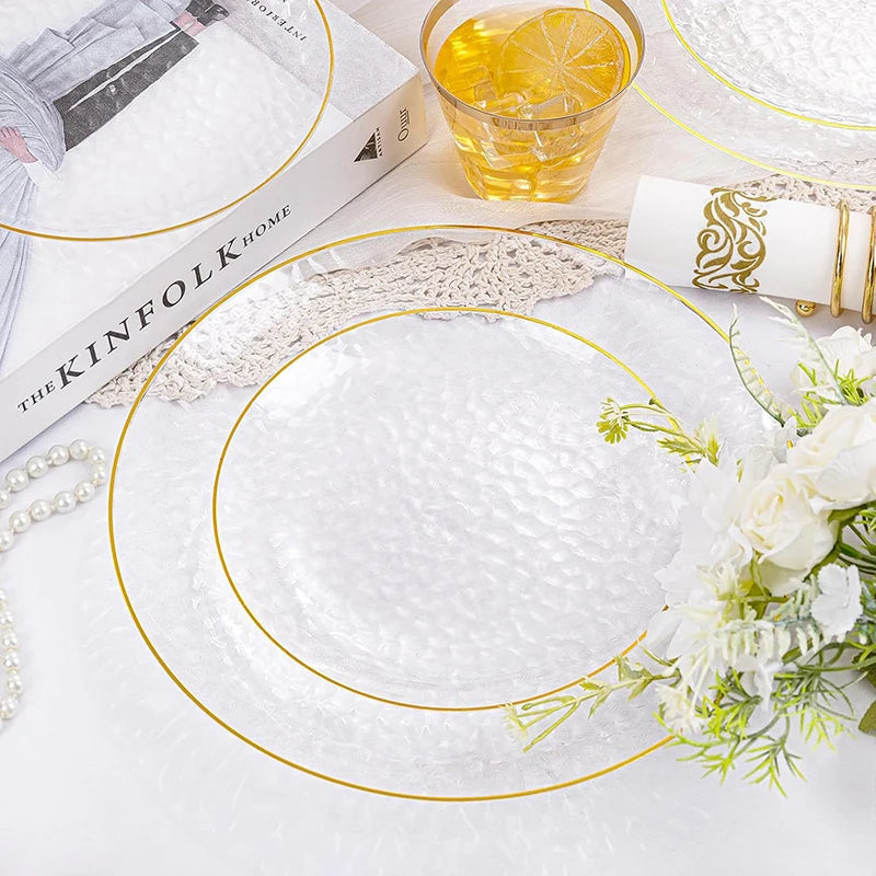 A set of white disposable dinner plates with hammered gold rims and a natural linen napkin displayed on a white surface.
