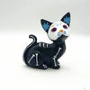 A black and white resin figurine set of a dog and cat face with blue flowers