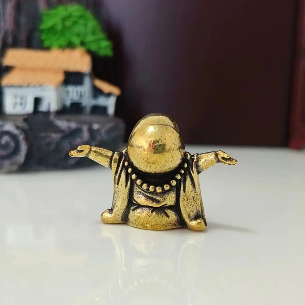 A small brass statue of a laughing Buddha with outstretched arms, used for home decor.