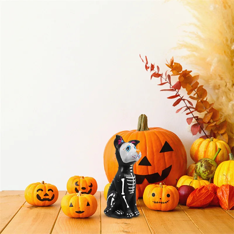 A set of resin figurines depicting a dog and cat carved into jack-o'-lanterns surrounded by autumn foliage.