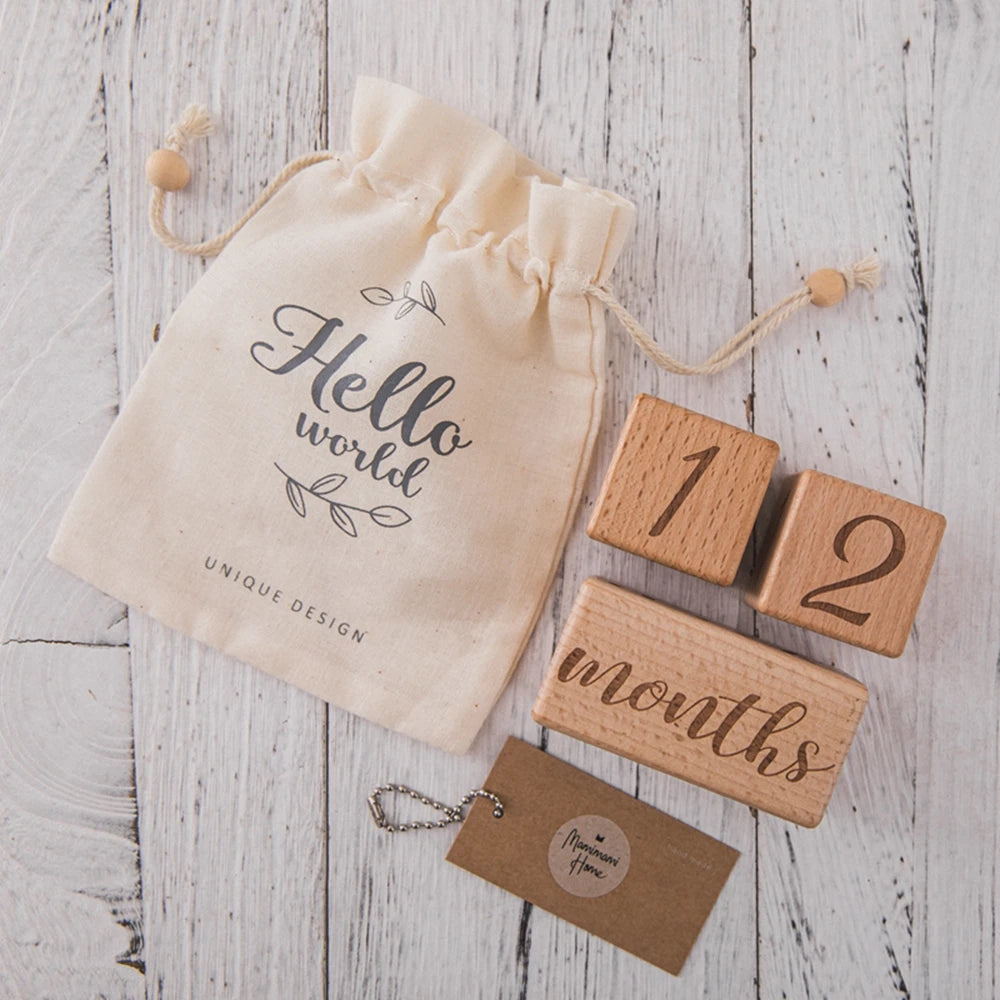 A beige fabric pouch tied with twine holds wooden baby milestone cards marked for 12 months.