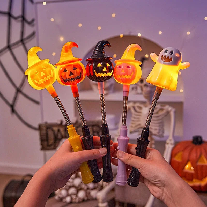 Une main tient une canne de lanterne d'Halloween orange lumineuse avec un motif de citrouille sculptée sur un arrière-plan fl