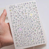 A hand holds a sheet of glitter gem stick-on facial tattoos showing various colored gems.