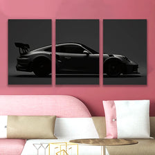 Three panels of black sports car silhouette wall art displayed above a pink sofa.