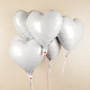 A cluster of ten white heart-shaped foil balloons tied together on a string.