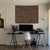 A large leopard print tapestry wall hanging is displayed above a desk with a computer monitor and accessories.