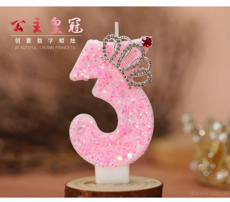 Pink glitter number three birthday candle with a crown topper on a wooden base