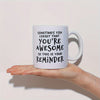 A white ceramic coffee mug with black text that reads Sometimes you forget that you're awesome so this is your reminder