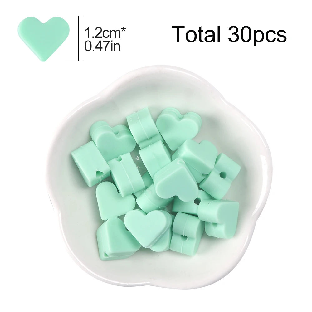 A white dish filled with 30 light green silicone heart beads for DIY jewelry making