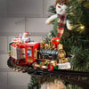 A battery-powered train toy is displayed in a festive Christmas tree setting with a snowman decoration.