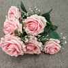 A bouquet of pink silk peonies with green leaves and small white filler flowers.