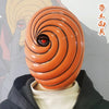 An orange, spiraled ninja mask with a red eye is displayed against a background featuring an Uchiha character.