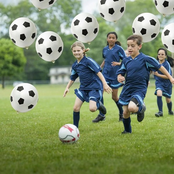 Kinder spielen Fußball auf einem grünen Feld, während Ballons in Form von Fußbällen über ihnen schweben.