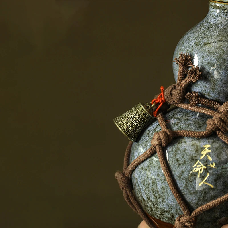 A dark blue ceramic wine gourd tied with brown twine and featuring gold-colored decorative elements.
