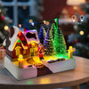 Illuminated Christmas village scene featuring a house, Santa, and snowy evergreen trees with string lights.