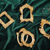 Several ornate vintage gold frames and decorative borders displayed on a dark emerald green velvet fabric.