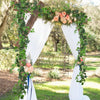 An archway decorated with greenery and roses, used as a backdrop for an outdoor event.