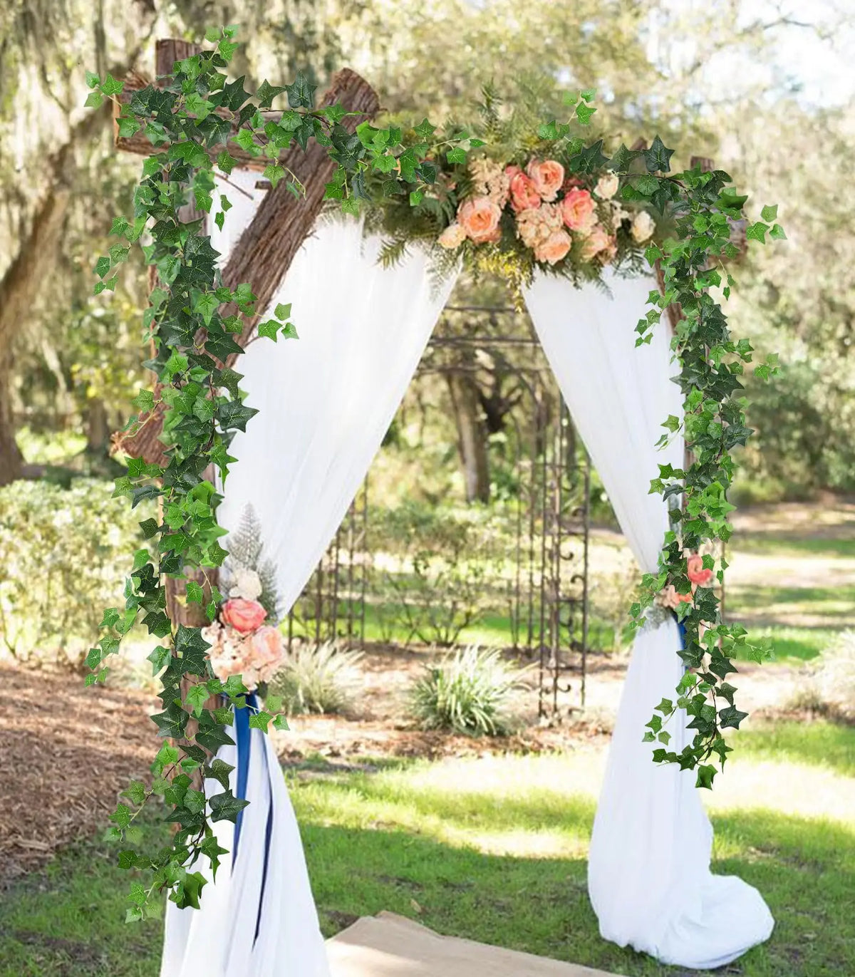 An archway decorated with greenery and roses, used as a backdrop for an outdoor event.
