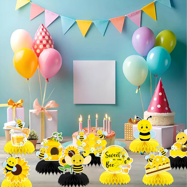 Un juego de tres centros de mesa de colmena y girasol de papel con globos amarillos, rosas y verdes y elementos decorativos.