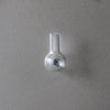 A clear glass fridge magnet with a narrow neck and a circular depression on the base.