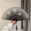 A black antique style bamboo folding hand fan is shown open against a light background.