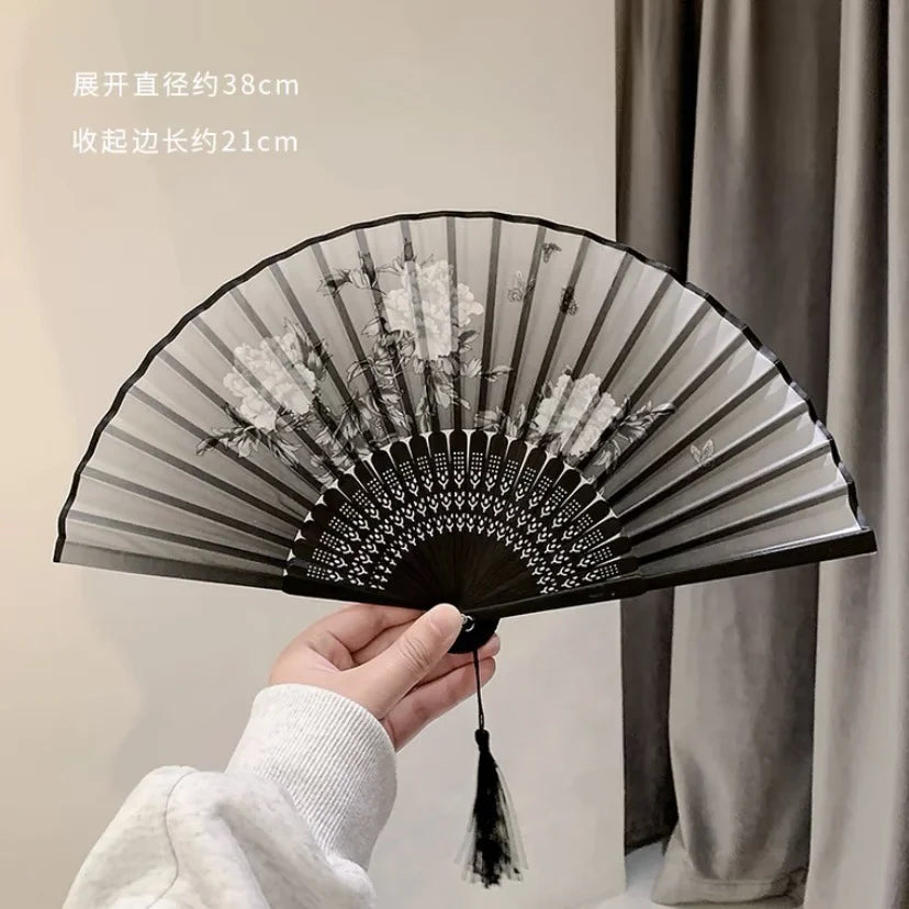 A black antique style bamboo folding hand fan is shown open against a light background.